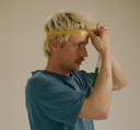 Person measuring head circumference with a yellow measuring tape against a beige background