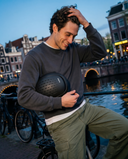 Man holding a black helmet by a canal with historic buildings in the background. headfirst Echo Pro Black Chris 7