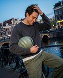 Man holding a helmet by a canal with historic buildings in the background. headfirst Echo Pro Green Chris 5