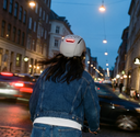 Person wearing an Echo Pro Beige headfirst helmet with a brake light on a city street at night.