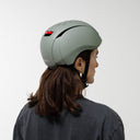 Side view of a person wearing an Echo Pro Green headfirst helmet with a red brake light bar, set against a plain light gray background.
