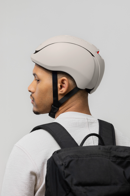 Person wearing a white helmet and carrying a black backpack on a light gray background. headfirst_binnen_shoot Echo Pro black Jeremy 2