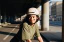 Person wearing a helmet sitting on a bench under an overpass. headfirst helmets Echo Pro Beige Sue 